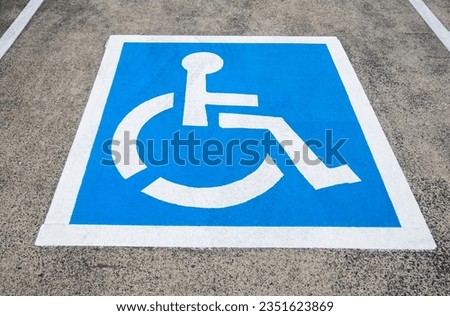 Reserved parking sign for handicapped. Disabled parking space with white blue painted sign of handicapped parking spot. Handicapped parking spot, blue square on asphalt. Accessibility concept. Royalty-Free Stock Photo #2351623869