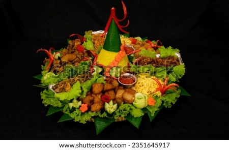 Tumpeng (Javanese) is an Indonesian cone-shaped rice dish with side dishes of vegetables and meat originating from Javanese cuisine of Indonesia. Isolated picture, black background
