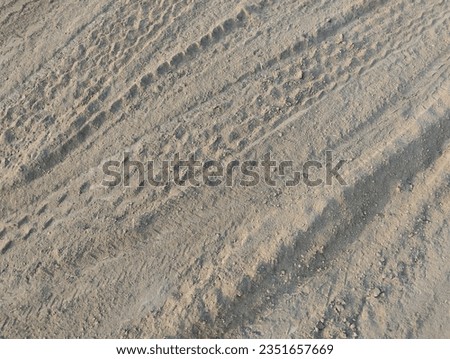 Tire tracks through a dry dirt ground. Texture of gravel road with car wheel tracks. Sand surface for background.  Close up view