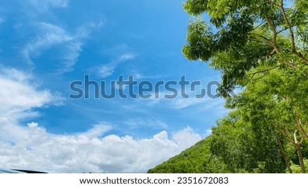 The blue sky and white clouds in summer cover forests and mountains.