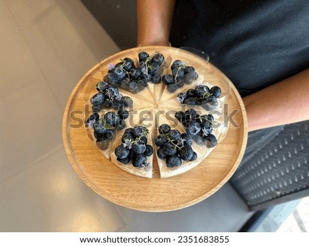 Woman holding plate with delicious Blueberry cheesecake. 
cheesecake on a wooden plate. Fresh Blueberry topping with cream and thyme leaves. Bakery picture free space for text.