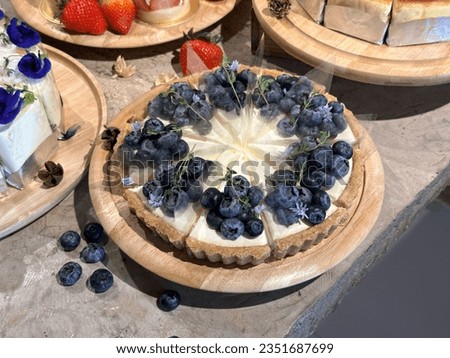 Delicious Blueberry cheesecake. 
cheesecake on a wooden plate. Fresh Blueberry topping with cream and thyme leaves. Bakery picture free space for text.