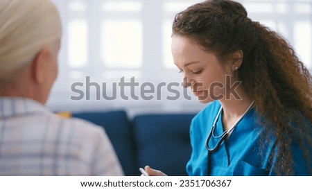Nurse with a stethoscope filling out medical forms, listening to female patient