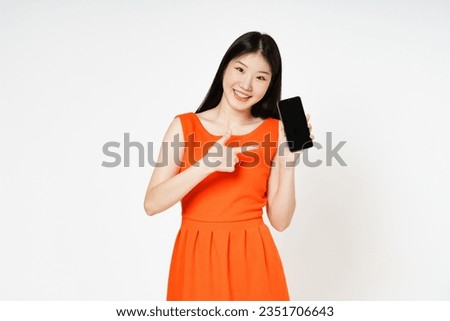 Smiling woman holding blank screen and pointing finger over white background.