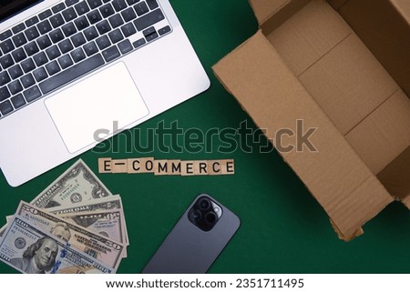 flat lay photo showing E-commerce lettering next to laptop, cardboard box. Selling products online