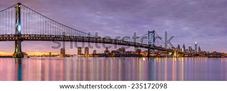 Panoramic view of the Ben Franklin bridge and Philadelphia skyline, under a purple sunset