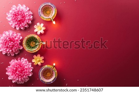Happy Diwali - Clay Diya lamps lit during Diwali, Hindu festival of lights celebration. Colorful traditional oil lamp diya on red background Royalty-Free Stock Photo #2351748607