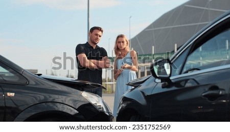 Drivers got into an accident and are standing near cars on the road. Two people man and woman talk argue on bad situation wait for the police outdoors.
