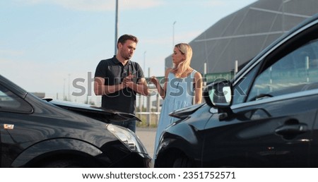 Drivers got into an accident and are standing near cars on the road. Two people man and woman talk argue on bad situation wait for the police outdoors.