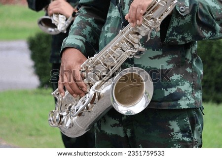 A male musician holding a saxophone in the back