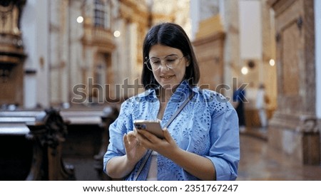 Young beautiful hispanic woman visiting church using smartphone standing at St. Karl BorromÃ¤us church