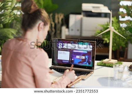 Seen from behind modern business woman with laptop using text to image ai image generator in modern office.