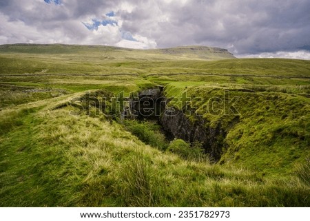 View along the full length of Hull Pot. A colapsed cavern near Penyghent in Ribblesdale in the Yorkshire Dales. Pen-Y-Ghent is the mountain in the distance. Royalty-Free Stock Photo #2351782973