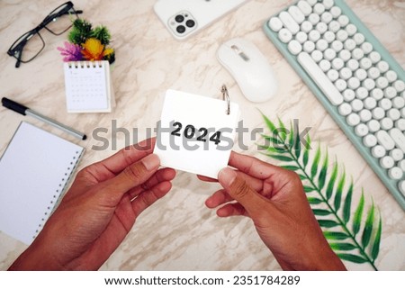 Male hand holding table calendar with white marble background. To-do list and plans for 2024 Goals for next year. 