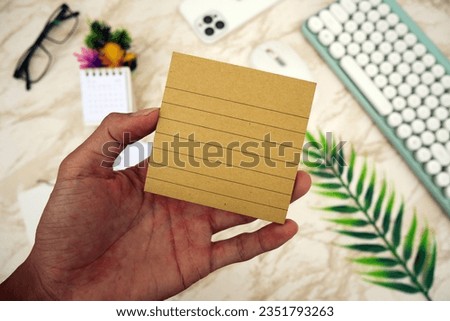 Brown notebook in male hand against white marble worktop background