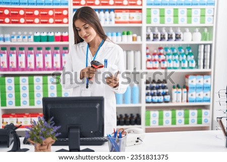Young beautiful hispanic woman pharmacist scanning pills bottle at pharmacy