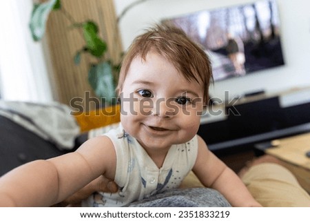 Smiling happy baby boy making selfie by own hand