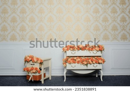 a buch of peach and orange flower on the white table in a room with white wall profile and gold wallpaper
