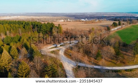 Aerial view along road between the fields and golden fall forest of north america. Farming, fields with harvest, north american golden fall forest is best tourist place in fall to camping and photo.