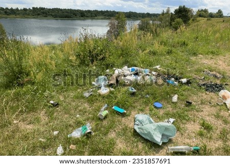 People throw garbage near lake in nature. Trash at camping resort. Garbage dump in Illegal location. Pile of rubbish in nature. Environmental pollution and ecology. Illegal dumping of Garbage.  Royalty-Free Stock Photo #2351857691