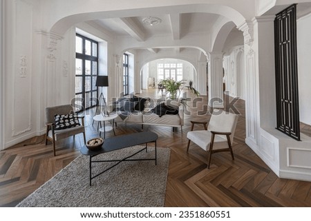 a chic expensive bright interior of a huge living room in a historic mansion with arched arches, columns and white walls decorated with ornaments and stucco. Royalty-Free Stock Photo #2351860551