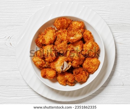crispy fried panko breaded chicken bites in white bowl on white wooden table, horizontal view from above, flat lay, close-up Royalty-Free Stock Photo #2351862335
