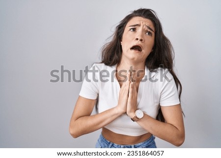 Young teenager girl standing over white background begging and praying with hands together with hope expression on face very emotional and worried. begging.  Royalty-Free Stock Photo #2351864057