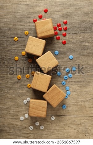 Wooden cubes with multi-colored buttons on a wooden background. World autism day concept