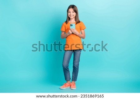 Full length photo of charming cute girl wear trendy orange clothes us modern gadget isolated on cyan color background