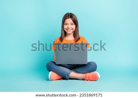 Photo of pretty cheerful girl wear trendy orange clothes sitting floor hold use wireless netbook isolated on cyan color background