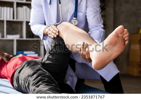 Physiotherapist treating patient at hospital Knee pain in male patient, physiotherapy concept Man stretching his foot with a band while doing physiotherapy at clinic
