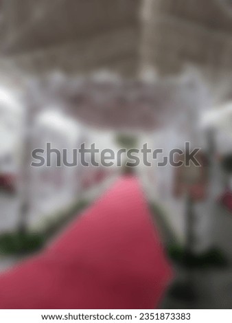 Blur photo Semi outdoor view for wedding venue concept. Decorated white entrance and red carpet with white flowers and curtains