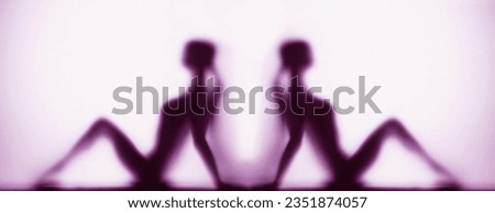 Silhouette of two women in yoga pose on a purple background panoramic