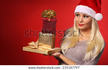 Santa Girl with Gift Boxes over red background. Christmas Portrait