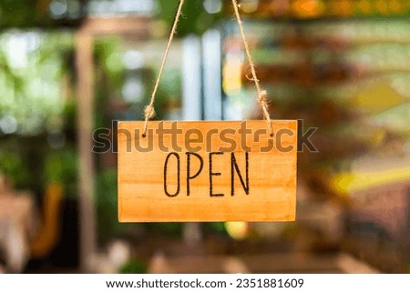 Wooden open sign in front of a cafe or shop with dissolved background