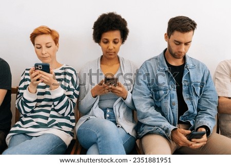 Cropped shot of bored multicultural and different ages people sitting in row using smartphones, waiting for job interview, human resources, employment or customers and electronic devices concept.