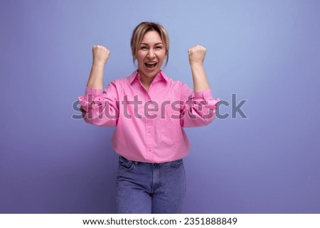 young well-groomed pretty european blonde secretary woman dressed in a pink shirt rejoices on a studio background with copy space