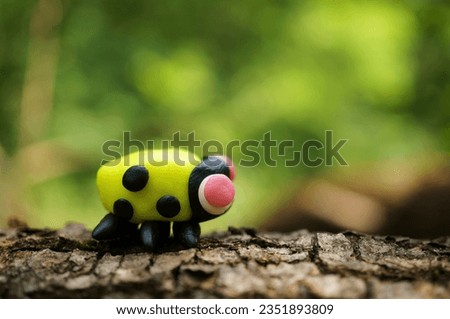 A figurine of a yellow ladybug. A toy animal.