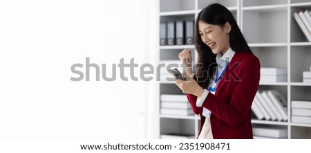 Successful Asian businesswoman happy looking at mobile phone and excited.