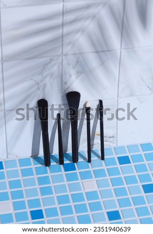 MAkeup brushes on tile with palm leaf shadow. Creative layout. Beauty still life