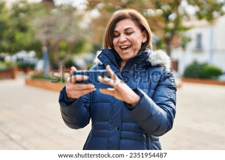 Middle age woman smiling confident watching video on smartphone at park