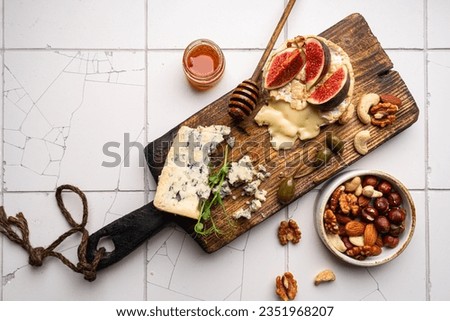Brie cheese on a wooden Board with fresh figs, gorgonzola and honey over white tail background, top view Royalty-Free Stock Photo #2351968207