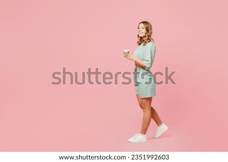 Full body side view young happy woman she wear casual clothes look camera hold takeaway delivery craft paper brown cup coffee to go isolated on plain pastel light pink background. Lifestyle concept Royalty-Free Stock Photo #2351992603