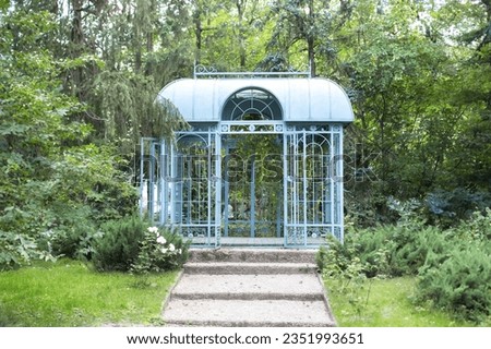  Large iron blue gazebo for relax outdoor. Wedding decorations. exterior Romantic alcove. Decor autumn terrace. Wrought metal gazebo in summer garden. Flowers in pots near porch. Sofa in spring gazebo Royalty-Free Stock Photo #2351993651