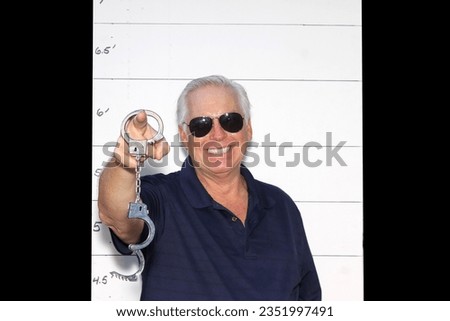 Photo Booth. A man Smiles and Laughs as his Mugshot Photos are taken during an arrest. A man Poses in a Photo Booth against a Mugshot Photo board. People love Photo Booth. Funny Photos. Pictures. 