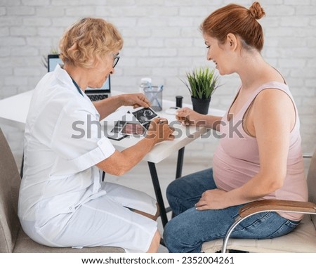 Obstetrician gynecologist explaining the screening picture to a pregnant woman. 