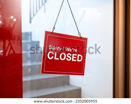 Shop closed, red and white notice sign with words "Sorry ! we're closed" hanging on glass door in front of the staircase in the hotel or restaurant. No service business store sign concept.