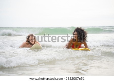 Young man and woman having fun with surfboard in the ocean on a sunny day