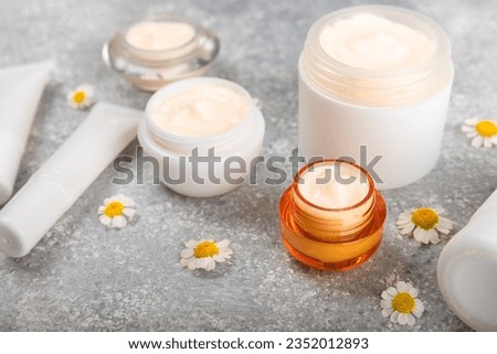 Open jar of cream for face, body and hands with chamomile flower on a blue background. Herbal dermatological cosmetic hygiene cream. Natural cosmetic product. Beauty concept. Cosmetic tube.MOCKUP