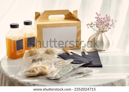 Composition of ramen soup ingredients in vacuum bags alongside carton box and bottles with stock on table in light room